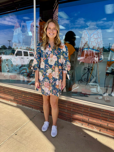 Floral print ¾ bubble sleeve mini dress featuring fixed bow accent ruffle V-neck. Pockets at sides.